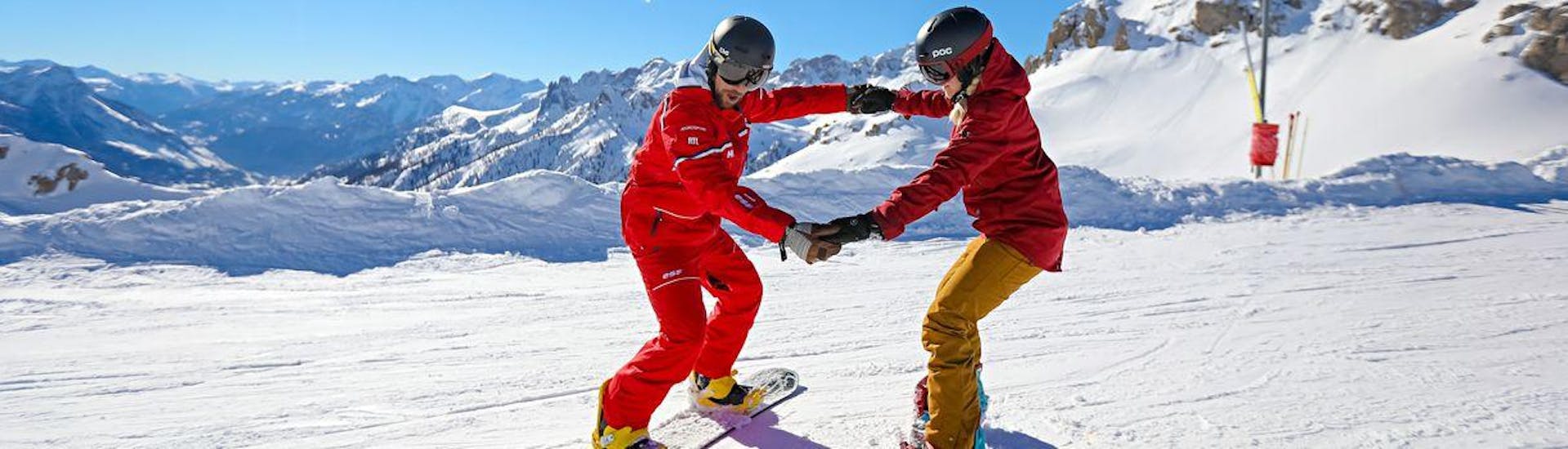 A snowboarding instructor from the ski school ESF du Dévoluy is showing the snowboarder apprentice the basics of snowboarding during his Snowboarding Lessons (from 8 years) - All Levels.