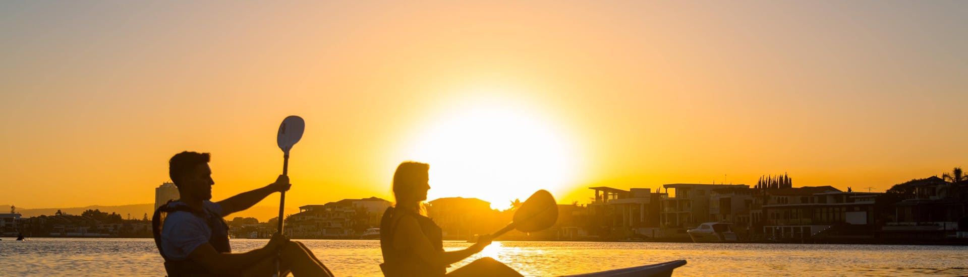 A couple is enjoying the Kayaking on the Gold Coast around Surfers Paradise at sunset organised by Australian Kayaking Adventures.