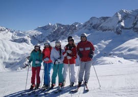 Children stand on a sunny day on the white piste and laugh into the camera during the kids ski lessons (6-14 years) - beginner from the ski school Escuela Española de Esquí Panticosa.