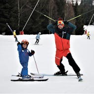 Tijdens de privéskilessen voor kinderen - alle niveaus leert een klein kind skiën onder toezicht van een ervaren skileraar van de skischool SnowMonkey in Špindlerův Mlýn.