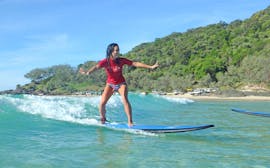 A young woman is all smiles as she rides her first waves during the Noosa surf lessons for beginners with Epic Ocean adventures Noosa.