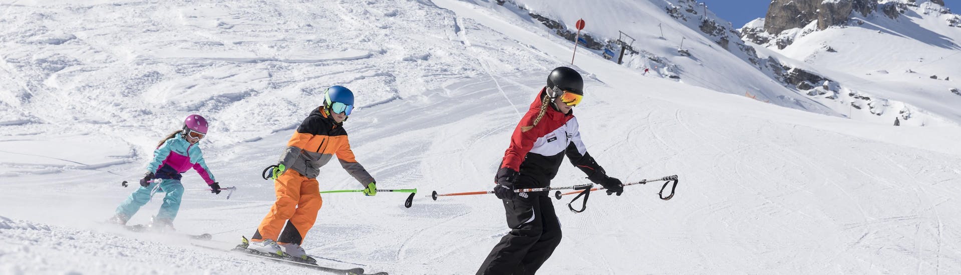 Three skiers are riding down a slope during their kids ski lessons christmas in Stubai.