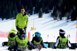 Un istruttore parla con i bambini durante una delle Lezioni private di snowboard - Tutte le età e livelli organizzate dai Maestri di Sci Cristallo - Monte Bondone nel comprensorio sciistico del Monte Bondone.