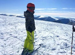 A skier is standing at the top of a slope waiting to start their Private Ski Lessons for Kids - Holidays with the ski school Moonshot La Bresse.