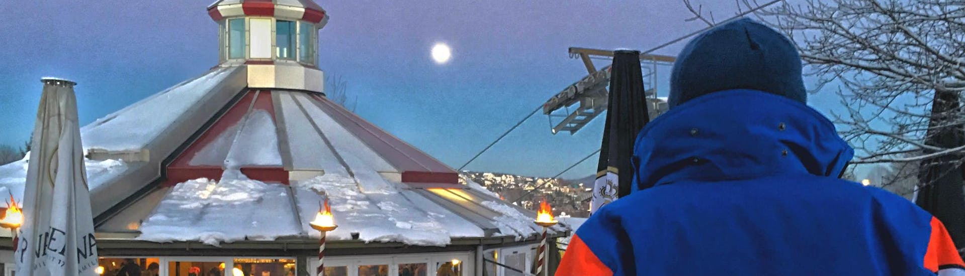 A ski instructor of the ski school Neue Skischule Winterberg is enjoying the view of the moon during the Night Ski Lessons for Kids & Adults - Beginners in Winterberg.