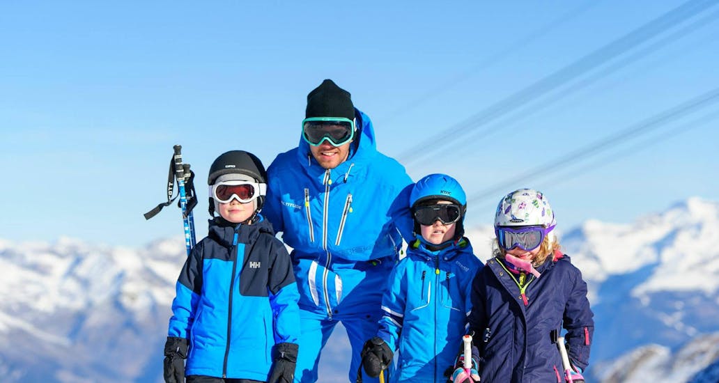 A ski instructor of Altitude Ski School Zermatt is posing for a photo with his students during the Private Ski Lessons for Kids - All Levels.