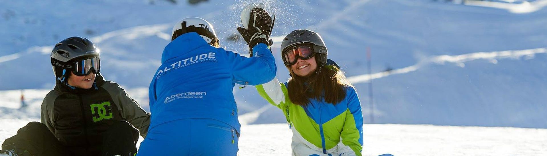 Una instructora de snowboard choca los cinco con su alumno durante las clases particulares de snowboard para niños y adultos - Todos los niveles con Altitude Ski School Zermatt.
