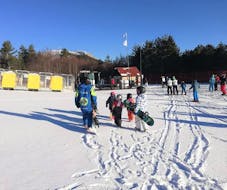 Un gruppo di snowboarder sta tornando alla base dopo una delle Lezioni di snowboard per bambini e adulti organizzate dalla Scuola di Sci Tre Nevi Ovindoli nel comprensorio sciistico di Ovindoli sul Monte Magnola.