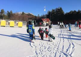 Snowboarding Lessons for Kids & Adults (from 8 y.) for Beginners with Scuola di Sci Tre Nevi Ovindoli A group of young snowboarders is heading back to the base after taking part in the Snowboarding Lessons for Kids & Adults organized by the ski school Scuola di Sci Tre Nevi Ovindoli in the ski resort of Ovindoli on the Monte Magnola.