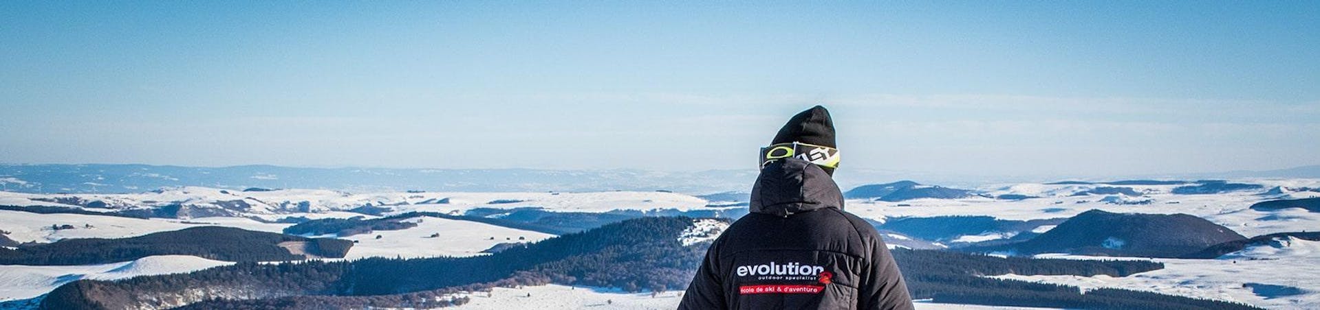 Un skieur contemple le paysage enneigé à ses pieds pendant son Cours particulier de ski pour Enfants - Tous âges avec l'école de ski Evolution 2 Super Besse.