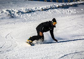 Un snowboardeur dévale une piste de poudreuse en confiance pendant son Cours particulier de snowboard pour Enfants & Adultes avec l'école de ski Evolution 2 Super Besse.
