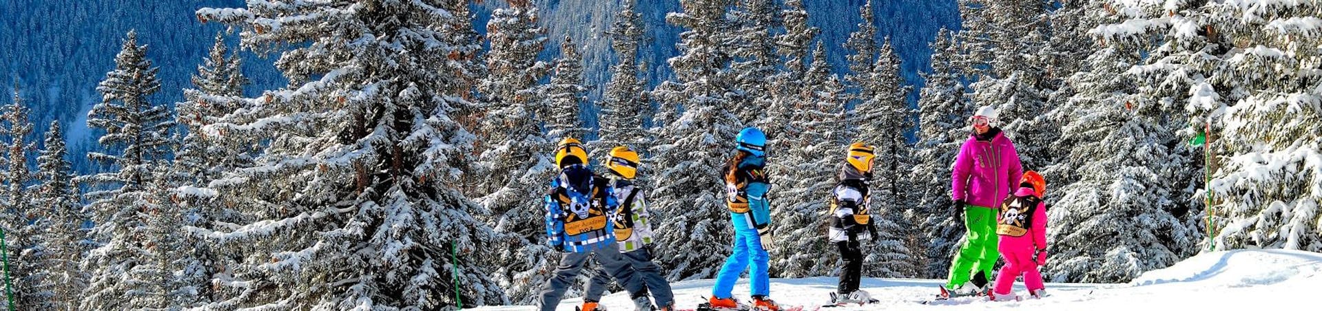 Un groupe de skieurs suit leur moniteur de ski de l'école de ski Evolution 2 Super Besse devant un paysage de forêt enneigé pendant leur Cours de ski pour Enfants (6-13 ans) - 9 au 14 février.
