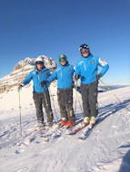 Un gruppo di maestri privati delle Lezioni private di sci per adulti - Tutti i livelli organizzate dalla Scuola di Sci Pinzolo nel comprensorio sciistico della Val Rendena sta sorridendo alla fotocamera su una pista innevata e soleggiata.