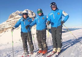 Un gruppo di maestri privati delle Lezioni private di sci per adulti - Tutti i livelli organizzate dalla Scuola di Sci Pinzolo nel comprensorio sciistico della Val Rendena sta sorridendo alla fotocamera su una pista innevata e soleggiata.