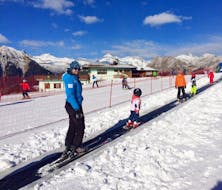 A ski instructor and his student are preparing for the Kids Ski Lessons (3-5 years) - First Timer organized by the ski school Scuola di Sci Pinzolo in the Val Rendena ski resort.