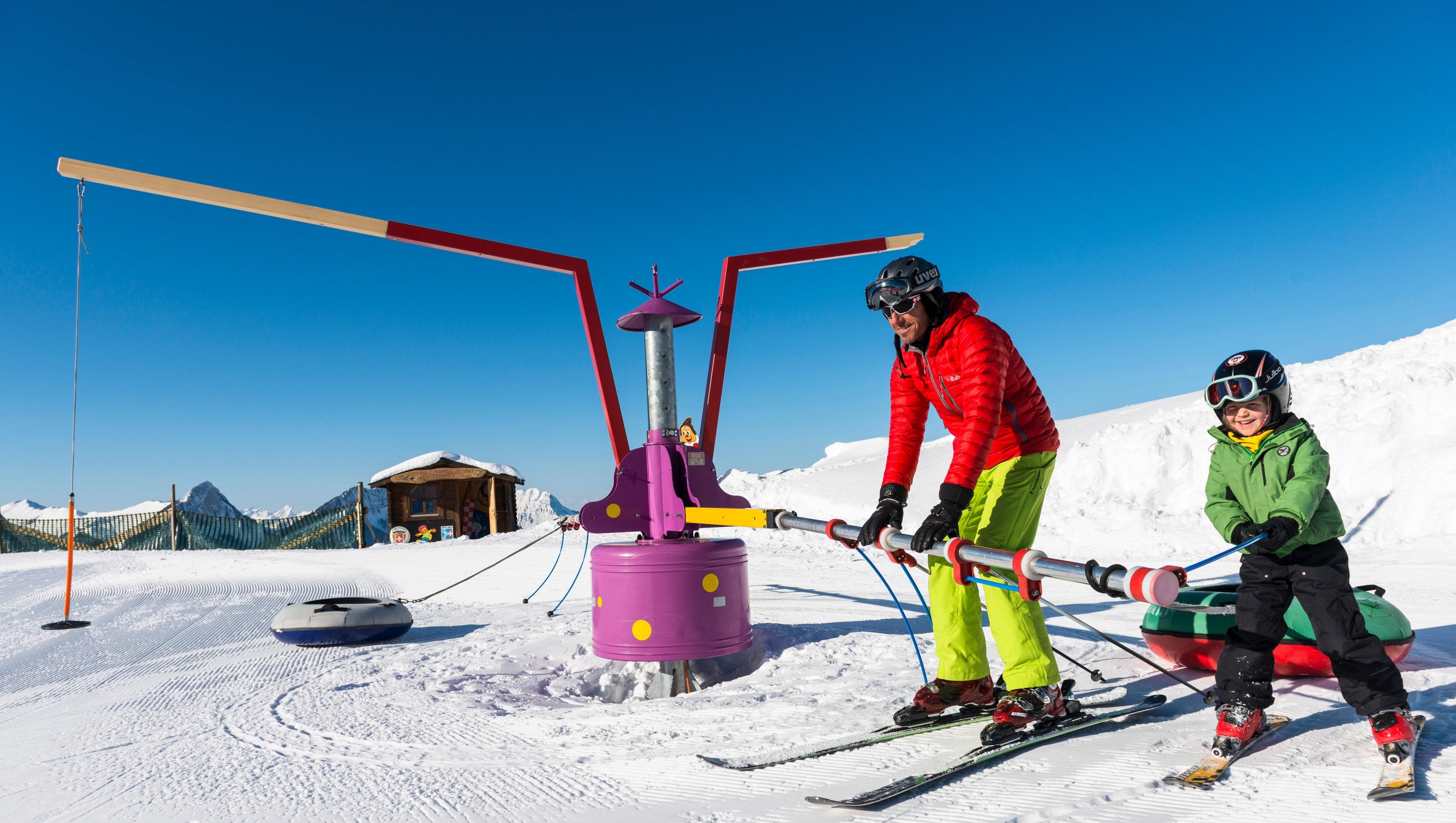 A kid is learning how to take the chairlift with the help of a ski instructor from the swiss ski school Charmey during their Ski Lessons "Kids Snow Garden" (3-5 years) - 1 day.