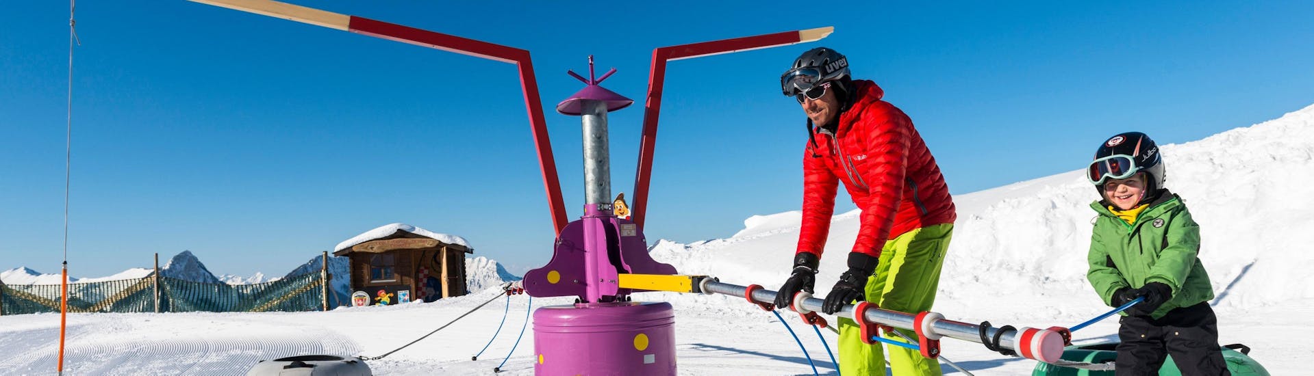 Ein Kind lernt beim Skikurs "Schnee-Kindergarten" (3-5 Jahre) - Schulferien mit seinem Skilehrer der Schweizer Skischule Charmey wie es den Sessellift benutzt. 