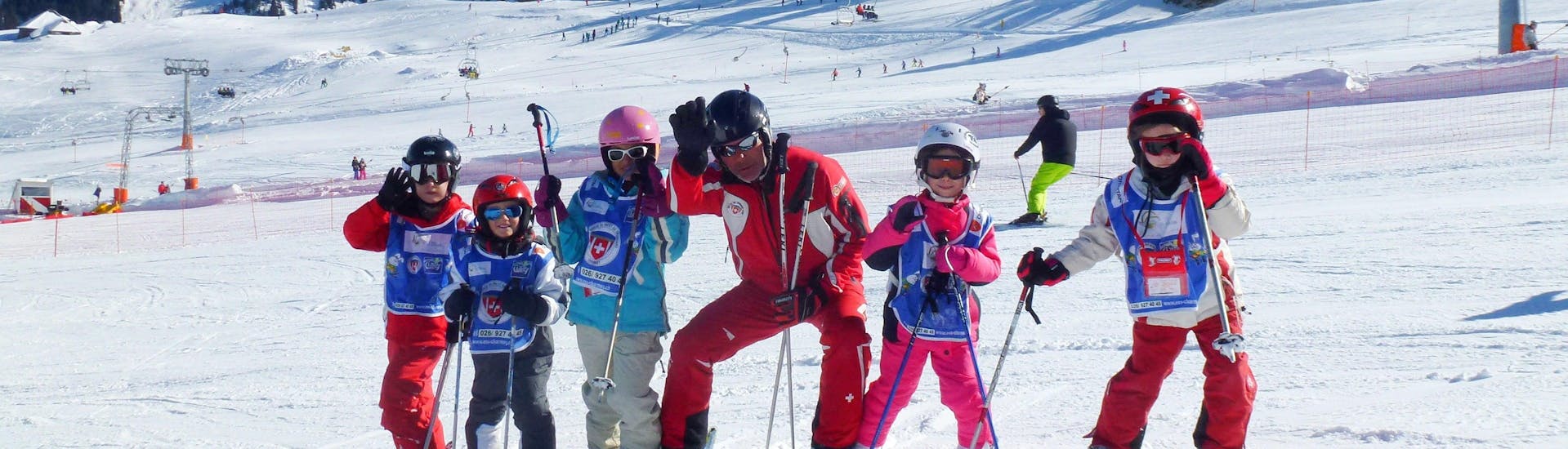 Eine Gruppe Kinder posiert beim Kinder Skikurs (6-15 Jahre) - Schulferien - Alle Levels der Schweizer Skischule Charmey für ein gemeinsames Gruppenfoto auf der Piste.