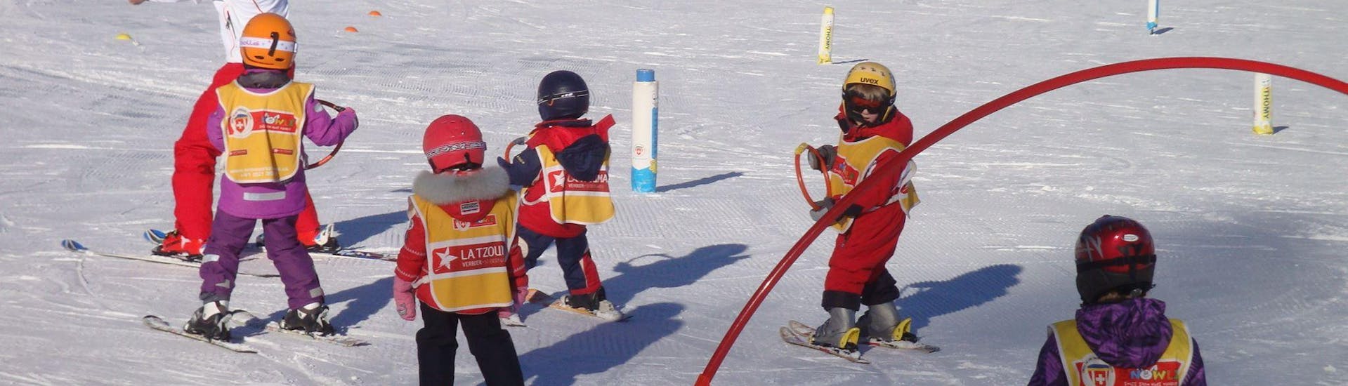 Eine Gruppe Kinder lernt beim Kinder Skikurs "Schneegarten" (3-6 Jahre) - Vormittag der Schweizer Skischule La Tzoumaz auf spielerische Weise im Kinderland das Skifahren. 