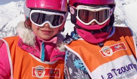 Due bambini sorridono alla macchina fotografica prima d'iniziare le lezioni di sci per bambini "Snowgarden" (3-6 anni) - Mattina con la Scuola di Sci Svizzera La Tzoumaz.