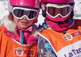 Deux jeunes enfants sourient à l'appareil photo avant de commencer leur Cours de ski Enfants "Jardin des neiges" (3-6 ans) - Matin avec l'école de ski suisse La Tzoumaz.