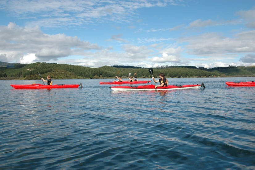 A group of people paddle in three kayaks on the calm lake during their kayak rotorua guided hot pools - winter - lake rotoiti with River Rats Rotorua Raft & Kayak.