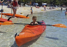 A child is trying to paddle a kayak during the Sea Kayak Rental - Makarska Riviera offered by Butterfly Diving & Sailing.