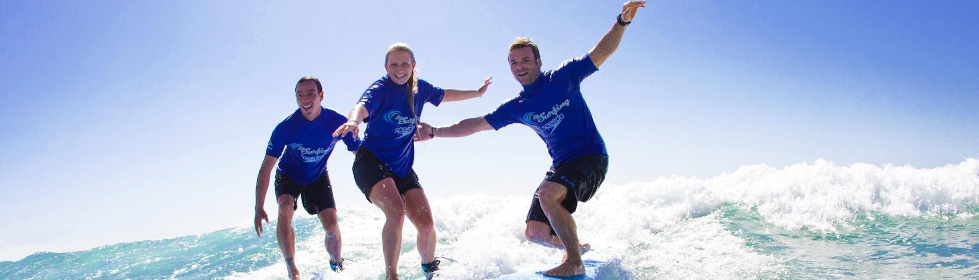 A group of friends is riding their first wave during the Surfing Lessons in Maroubra for Teens & Adults - Low Season offered by Let's Go Surfing Maroubra.
