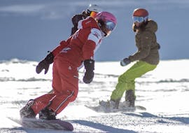 Snwoboarders learn to ride down a slope with their ESF Val Thorens instructor during a snowboarding lesson for teens and adults.