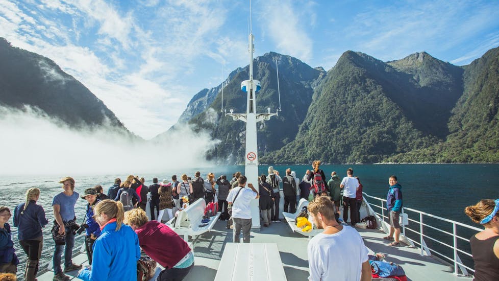 People are enjoying the spectacular views of mountainous area during the Milford Sound Cruise "Classic" - Winter organised by Jucy Cruise.