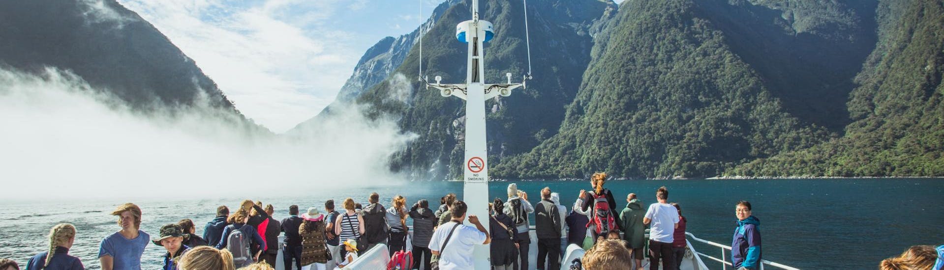 People are enjoying the spectacular views of mountainous area during the Milford Sound Cruise "Classic" - Winter organised by Jucy Cruise.