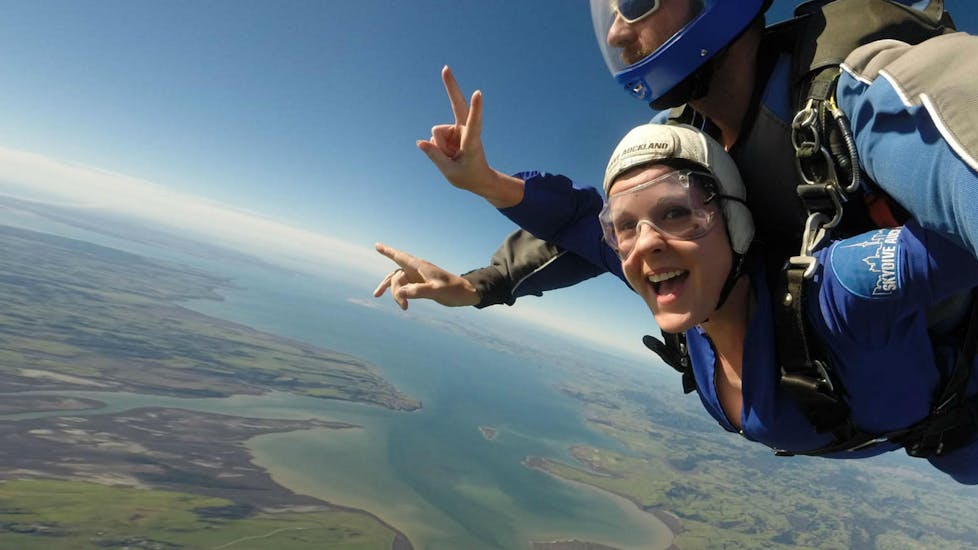A female skydiver is seemingly enjoying her Tandem Skydive in Auckland - 20,000ft with Skydive Auckland as she and her instructor look out over the beautiful North Island coast line. 
