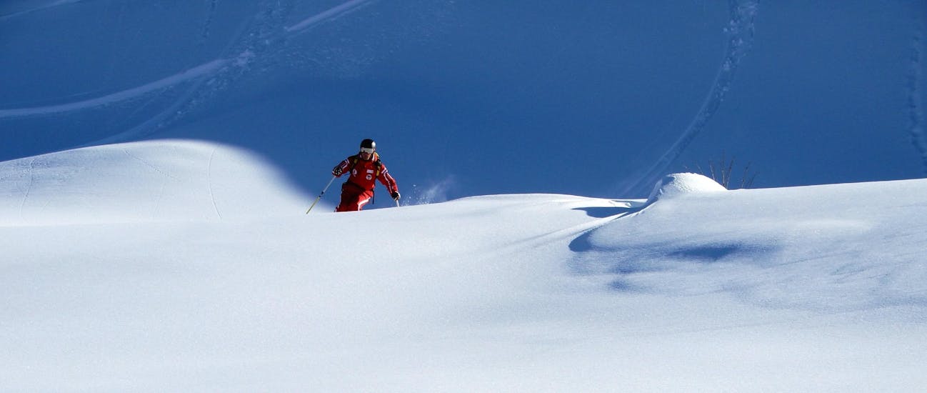 Een skileraar van de Zwitserse skischool La Tzoumaz en een skiër kijken uit over de bergen rond La Tzoumaz tijdens privélessen off-piste skiën - alle niveaus.