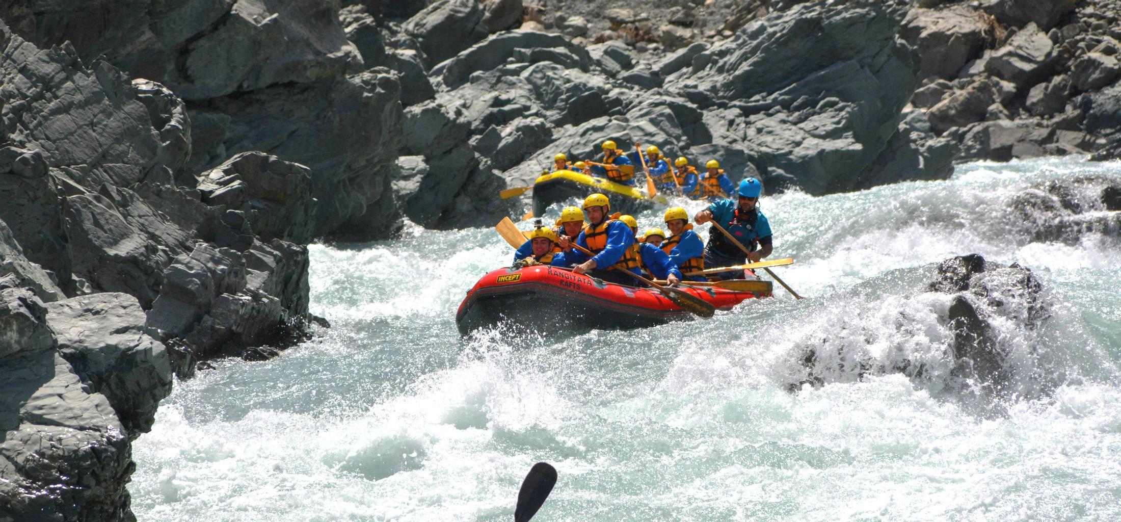 A group of rafters is paddling down a narrow section of the river during their Grade 5 Rafting Adventure in Rangitata Gorge organized by Rangitata Rafts.