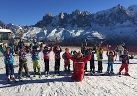 Des enfants se tiennent les uns à côté des autres avec leurs bâtons de ski en l'air pendant leur Cours de ski pour Enfants (5-12 ans) à Chamonix/Savoy avec l'école de ski ESF Chamonix.