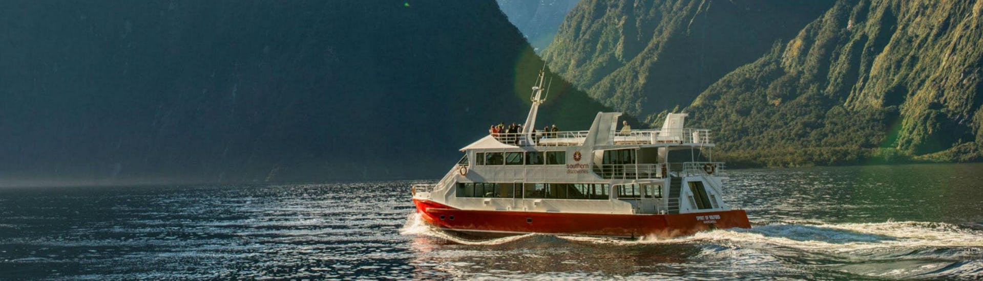 A Southern Discoveries catamaran is carrying a group of visitors along New Zealand's most famous fjord during the Nature Cruise in Milford Sound - Winter.
