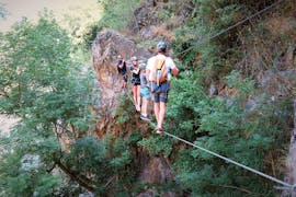 Des aventuriers passent un pont de singe surplombant un ravin pendant leur sortie Parcours Aventure de l'Aigle dans la Vallée de la Besorgues avec Les Intraterrestres.