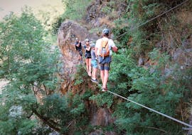 Des aventuriers passent un pont de singe surplombant un ravin pendant leur sortie Parcours Aventure de l'Aigle dans la Vallée de la Besorgues avec Les Intraterrestres.