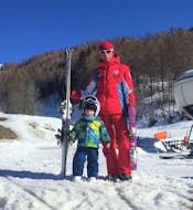 Un giovane sciatore sta sorridendo alla camera in compagnia del suo maestro privato di sci della Scuola di Sci Sauze Sportinia durante una delle lezioni private di sci per bambini - tutti i livelli sulle piste del comprensorio sciistico della Via Lattea.