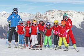 Two ski instructors are smiling at the camera with the young participants of the kids ski lessons (4-14 y.) - All Levels organized by the ski school Scuola di Sci Sauze Sportinia in the ski resort Via Lattea.