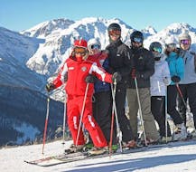 Des participants aux cours de ski pour adultes - tous niveaux organisés par l'école de ski Scuola di Sci Sauze Sportinia s'amusent avec le moniteur de ski dans la station de ski de Via Lattea.