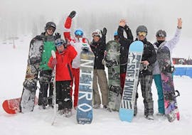 Un gruppo di parteicpanti delle Lezioni di snowboard per bambini e adulti - Tutti i livelli organizzate dalla Scuola di Sci Sauze Sportinia  sta sorridendo per una foto sulle piste del comprensorio sciistico della Via Lattea.