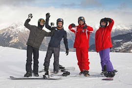Le moniteur des cours de snowboard freestyle particuliers - expérimentés organisés par l'école de ski Scuola di Sci Sauze Sportinia est souriant sur les pistes de la station de ski Via Lattea avec quelques participants à la leçon.