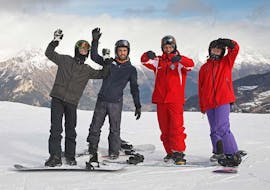 Le moniteur des cours de snowboard freestyle particuliers - expérimentés organisés par l'école de ski Scuola di Sci Sauze Sportinia est souriant sur les pistes de la station de ski Via Lattea avec quelques participants à la leçon.