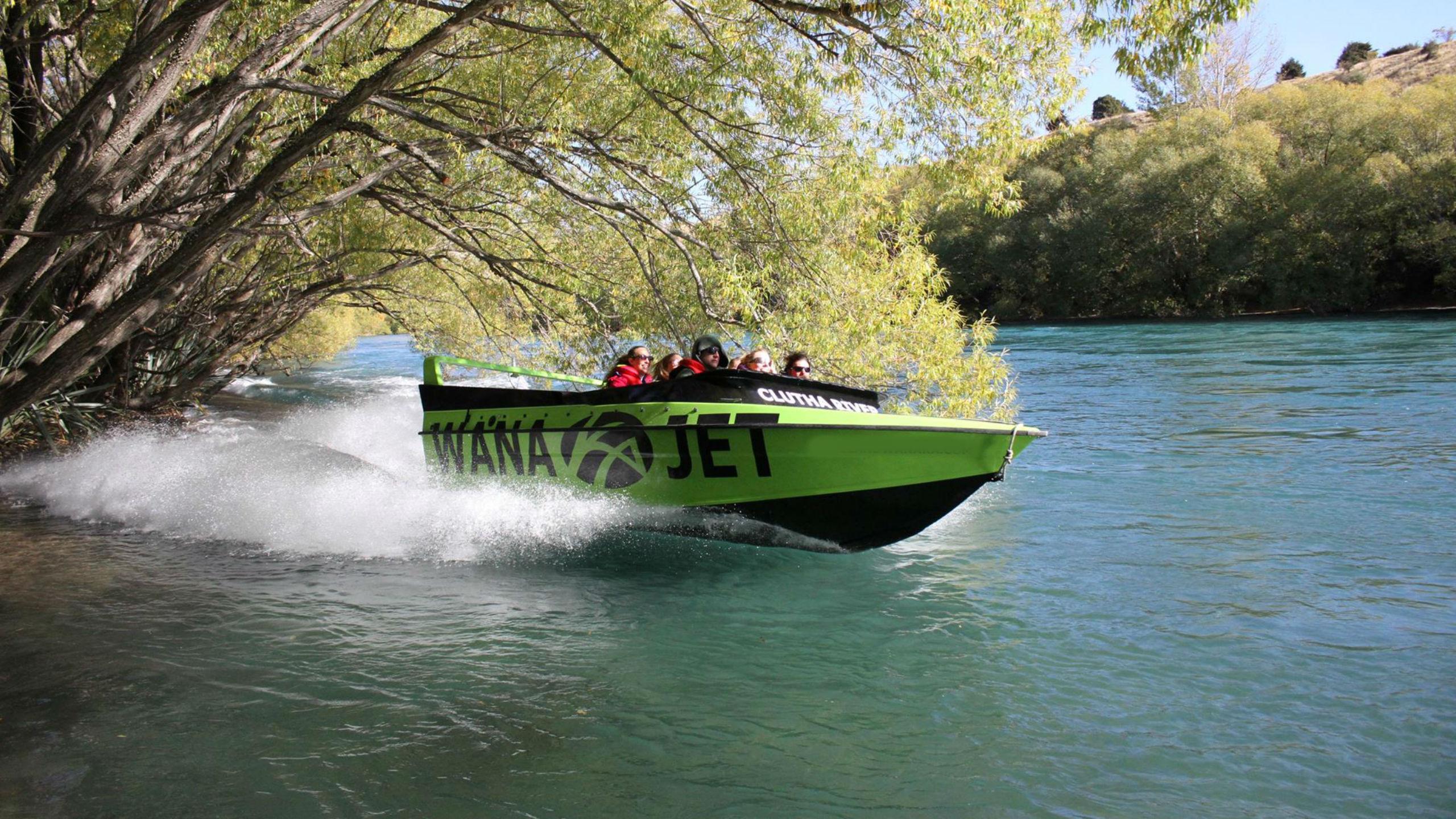 A jet boat operated by Lakeland Wanaka is speeding along Clutha River during the Wanaka Jet Boat Tour.