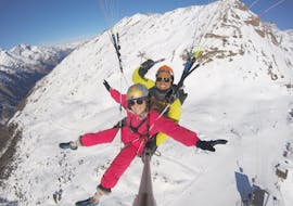 A tandem master and his passenger are flying over snowy Swiss mountains during the activity Tandem Paragliding "Explore" - Zermatt provided by Flybypara.