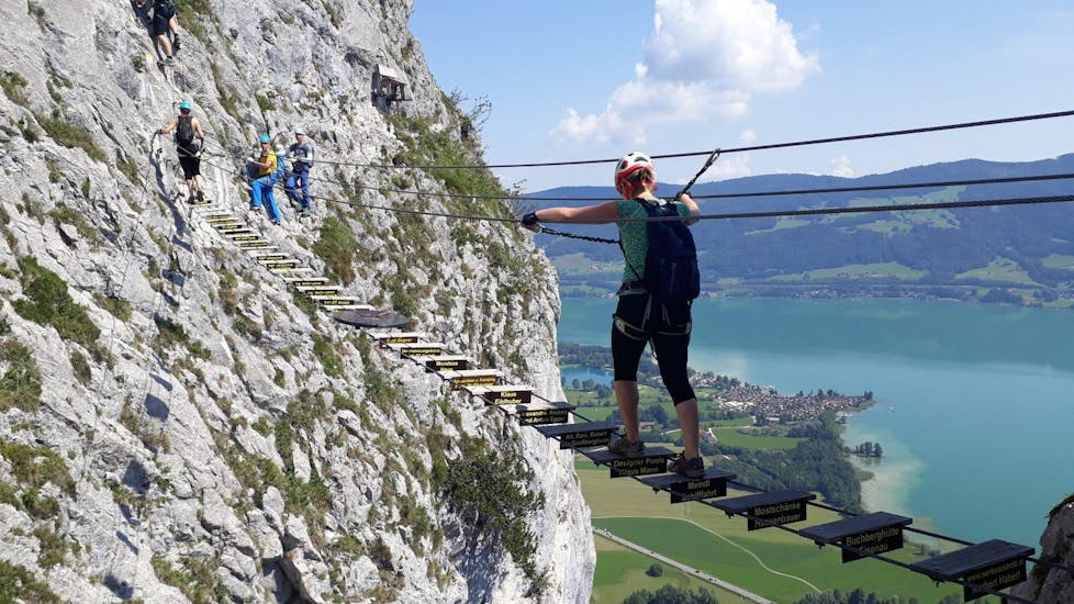 A woman crossing the adventurous suspension bridge of the Via Ferrata for panorama fans on the Drachenwand under the guidance of the experienced guides of Bergführer Salzburg.