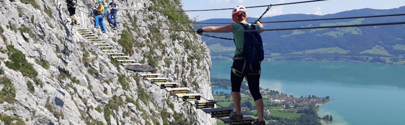 Een vrouw over de avontuurlijke hangbrug van de Via Ferrata voor panoramafans op de Drachenwand onder begeleiding van de ervaren gidsen van Bergführer Salzburg.