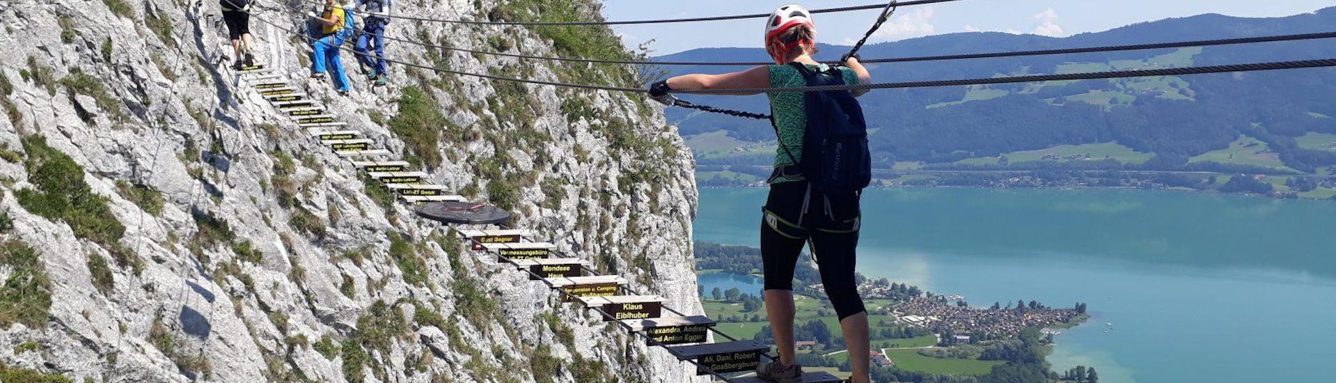Eine Frau, die die abenteuerliche Hängebrücke der Via Ferrata für Panoramafans auf der Drachenwand unter der Anleitung von den erfahrenen Guides von Bergführer Salzburg überquert.