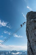 Eine Gruppe von Leuten, die bei Ihrer Klettersteig Tour für Mutige unter der Aufsicht der erfahrenen Bergführer von Bergführer Salzburg auf der spektakulären Himmelsleiter auf den Donnerkogel hinaufklettern.